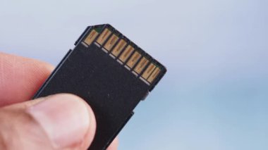 Bir kişi hafıza kartı tutar, konnektörlerini ve tasarımını gösterir.