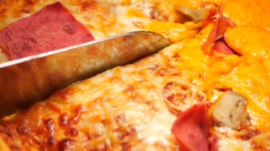 Bıçak, malzemelerle dolu peynirli pizzayı ustaca keser..