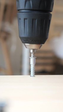 Montaj için tahta bir yüzeye vida sokacak bir matkaba odaklan..