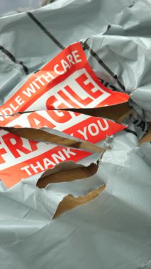 Hasarlı bir paket kapının önüne bırakılmış, yırtık ambalajlar görünüyor..