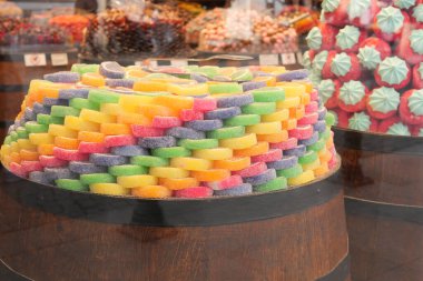 Parlak renkli şekerler bir market tezgahında canlı desenler halinde dizilmiş..