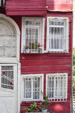 Büyüleyici kırmızı bina canlı çiçeklerle dolu beyaz pencere ızgaraları içeriyor.