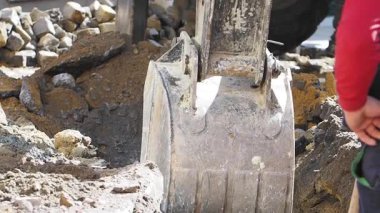 Kazıcı, binaların yakınındaki sokak bakımının bir parçası olarak kaldırımı kazıyor.