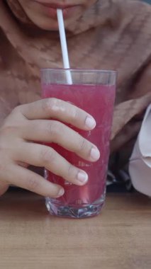 Bir el, bir kafede dinlenirken canlı pembe bir içecek tutar..