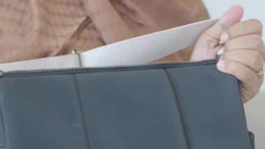 Bir insan şık bir çantayı ustalıkla parlak bir alana yerleştirir..