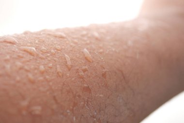 Su damlacıkları bir kolda parlar, yüzdükten sonra güneş ışığını yansıtır..