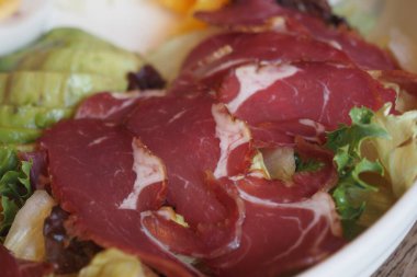 Çeşitli yeşillikler ve ince dilimlenmiş et içeren renkli salata..