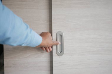 Bir insan nazikçe kapıyı açmak için kolu çeker..