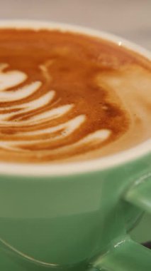 Yetenekli kahve ustaları sıcak bir kafede ustalıkla karışık latte sanatları icra ederler..