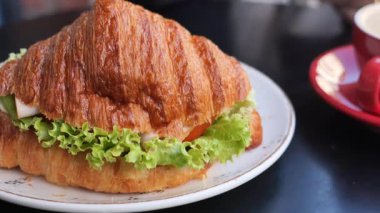 Taze marul ve domatesle dolu lezzetli bir kruvasan sandviçin tadını çıkarın..