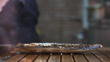 Bir şef, bugün kalabalık bir şehir pazarında ustalıkla taze balık pişiriyor..