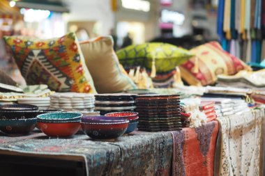 Parlak renkli kaseler ve tekstil ürünleri işlek bir pazarda sergileniyor..