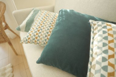 Yumuşak yastıklar, deniz mavisi ve desenli kumaşlar, hafif bir kanepede..