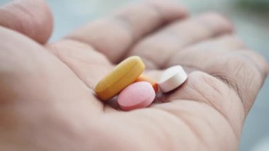 Bir el, çeşitli hapları canlı renklerde gösterir..