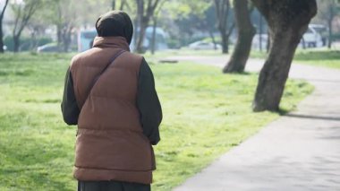 Bir insan yemyeşil bir parkta gezinir ve keyifli havanın tadını çıkarır..