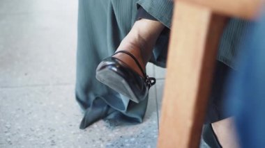 Şık siyah topuklu giyen biri yemek masasında rahatça oturur..