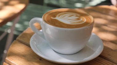 Bir kafede güneşli bir günde latte ile sanat eseri yudumlamak..