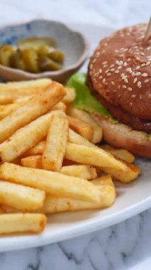 Lezzetli hamburger, yerel bir lokantada kızarmış patates ve turşuyla servis ediliyor..