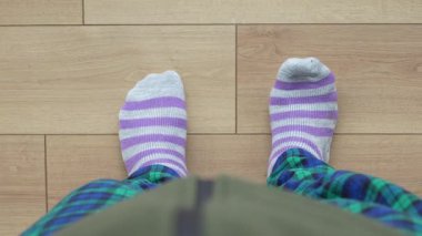 Evde çizgili çorap ve ekose pijama pantolon giyen biri var..