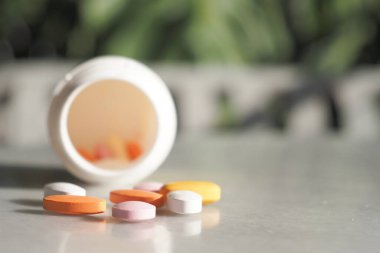 Devrilmiş bir ilaç şişesinden çeşitli renkli haplar dökülmüş..