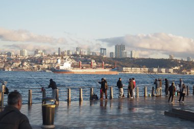 Balıkçılar rıhtımda kuyruk oluşturuyorlar, gemiler geçerken denize dökülüyorlar..