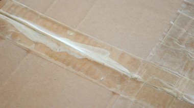 Kutuları açmak için bandın karton kutudan çıkarılışını izleyin..