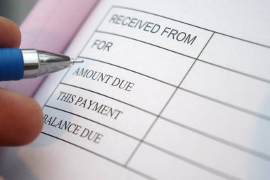 Bir kişi bir işlemin makbuzunu bir kalemle dolduruyor.