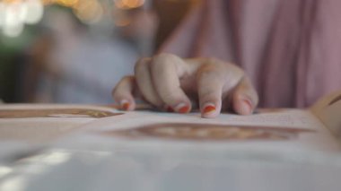 Bir kafede atmosferin tadını çıkarırken bir menüye el gezdirmek.