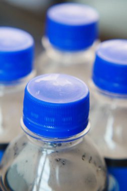 Düz bir yüzeyde mavi kapaklı su şişelerine yakın çekim.