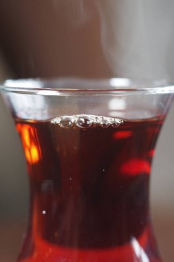 Temiz bardaktaki sıcak çay buhar ve kabarcıkları yukarı doğru gösteriyor..