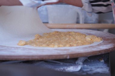 Elleri hamuru kıvrak bir mutfakta lezzetli bir dolguyla yuvarlıyor..