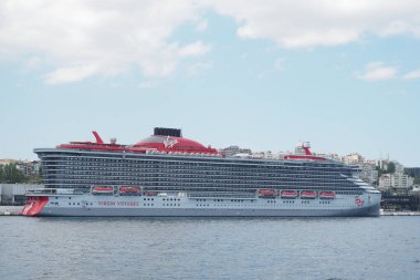 Bir yolcu gemisi güneşli bir günde yoğun bir limana demir atar..