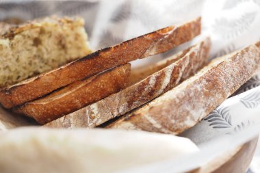 Paylaşmak için ahşap bir tabakta düzenlenmiş zanaatkar ekmeği dilimleri.