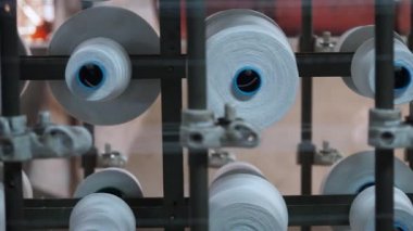 Bir tekstil atölyesinde modern makineler kullanarak ipliğin dönüş sürecini izleyin.