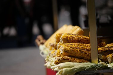 Bir sokak satıcısı gün içinde koçanda taze kızarmış mısır sunuyor..
