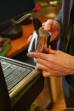 Yetenekli bir barista işte espresso makinesi kullanarak süt buharlaştırır..