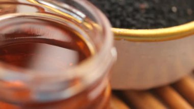 Arka planda siyah tohumlar olan bir kavanozda yağ yakın plan..