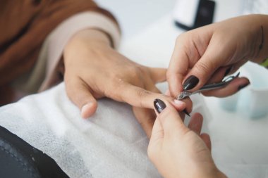 Yetenekli bir tırnak teknisyeni manikür sırasında dikkatlice tırnak şekillendirir ve keser..