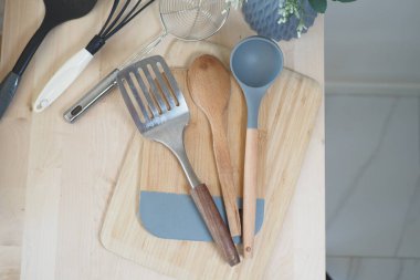 Çeşitli mutfak aletleri ahşap bir tahtaya düzgün bir şekilde oturur..