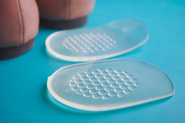 Mavi bir yüzeye yerleştirilmiş bir çift ayakkabının yanına yerleştirilmiş silikon ayakkabılar.