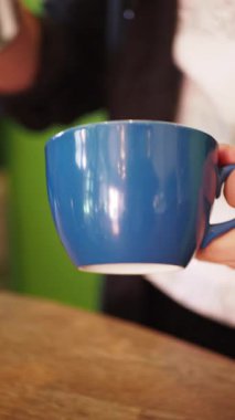 Bir insan hayat dolu bir kafe atmosferinde sıcak bir fincan kahvenin tadını çıkarır..