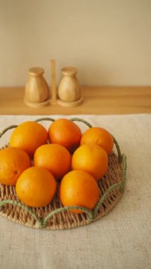 Sekiz taze portakal bir ışık masasında örülmüş sepetin içinde duruyor..