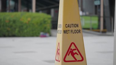 Sarı uyarı işareti, yoğun bir yerde ıslak bir zeminin olduğunu açıkça gösteriyor..