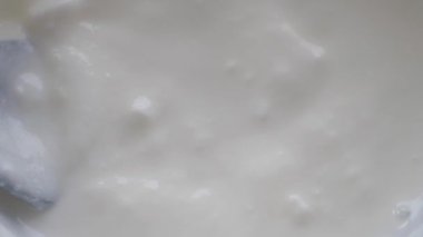 Evde beyaz bir kasede kalın, kremalı yoğurt karıştırıyorum..