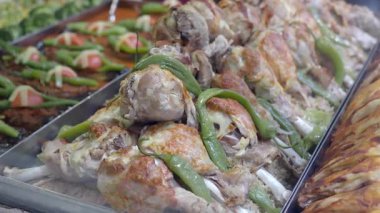 Sulu ızgara tavuk şişleri ve canlı sebzeler sunulur..