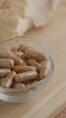 Bir kase tahtadan bir yüzeyde kahverengi bitkisel kapsüller içerir..