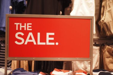 Kalın kırmızı tabela bir giyim mağazasında indirim ilan ediyor..