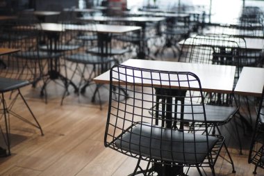 Şık kafe boş masalar ve geniş bir ortamda siyah metal sandalyeler içeriyor..