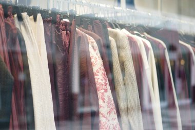 Çeşitli giysiler bir mağaza vitrinine asılır, yoldan geçenleri cezbeder..