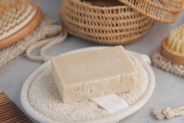 Doğal sabun, çevreci maddelerle çevrili dokuma bir tepside duruyor..